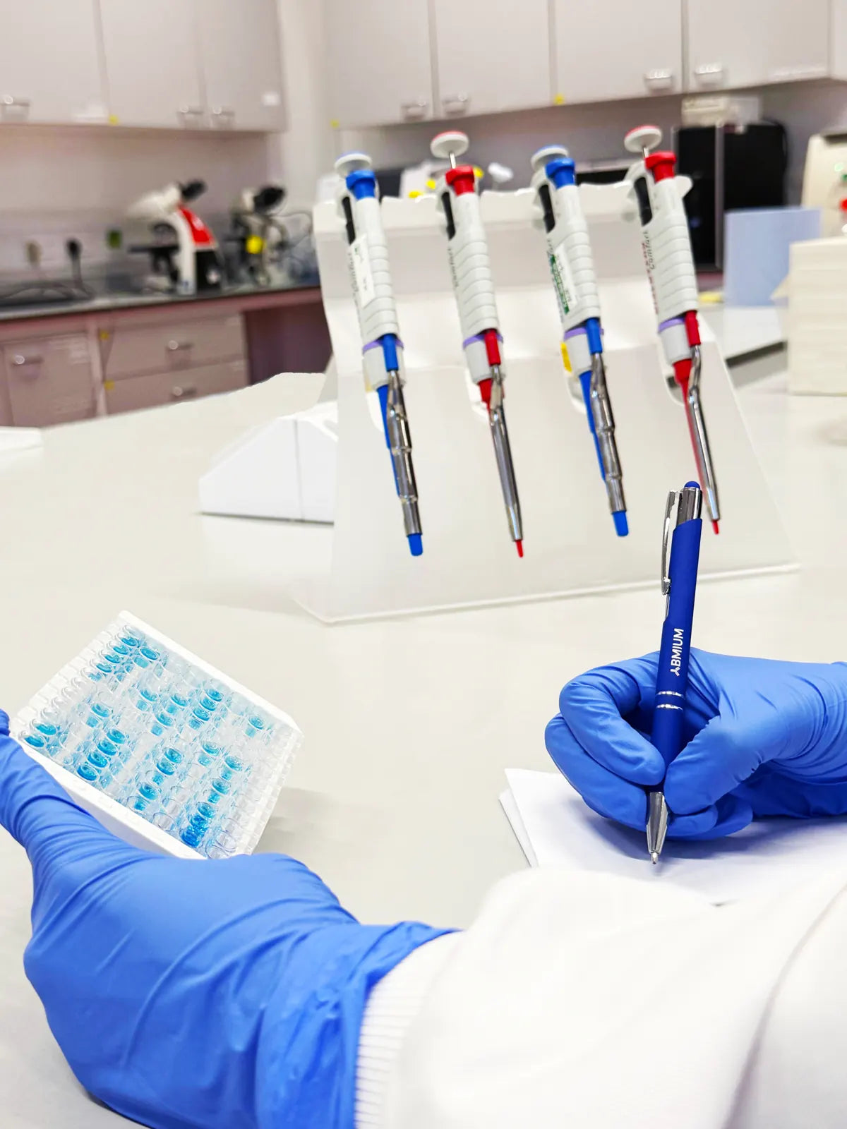 ABMIUM laboratory photograph with a microplate and ABMIUM-branded pen